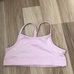 Ljusrosa sporttopp från SOC - En ljusrosa sporttopp från SOC med tunna axelband. Toppen har en silver SOC logga i ryggen. 