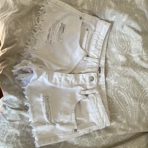 Vita jeansshorts från Sinsay - Snygga vita jeansshorts från Sinsay med slitna detaljer och fransig kant. Klassisk femficksmodell med knapp och dragkedja framtill. Perfekta för varma dagar när du vill ha en cool och avslappnad look. Storlek 34💞