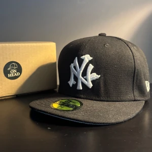 New Era keps - Säljer denna stilrena och exklusiva New Era 59FIFTY keps i klassiskt svart med New York Yankees-logga framtill och "2000 World Series" patch på sidan – ett måste för både samlare och stilmedvetna!  🟢 Storlek: 7 1/8 (56.8cm) 🟢 Modell: 59FIFTY Fitted 🟢 Färg: Svart med ljusblå underskärm 🟢 Skick: Nästan nyskick –  ”ny utan prislapp”  Perfekt för dig som vill lyfta din outfit med en keps som sticker ut men ändå håller det klassiskt. En keps som passar till det mesta! 🧢