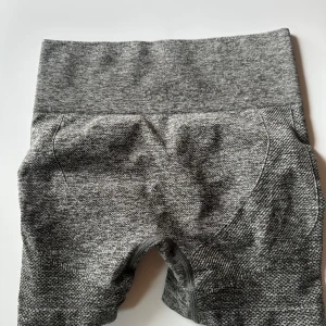 Grå sömlösa leggings med scrunch - Gråmelerade sömlösa leggings med hög midja och scrunch-detalj bak för extra shaping. Tillverkade i en mjuk och stretchig mix av polyamid, polyester och elastan. Perfekta för träning eller chill dagar. Sitter tight och formar snyggt.