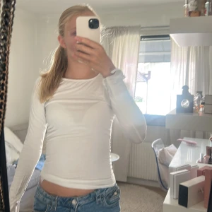 Vit långärmad topp i bomull - En enkel och stilren vit långärmad topp från Gina. Modellen är tight med rund hals och smala ärmar, perfekt att matcha med jeans eller kjol. Passar dig som gillar basic och clean look.