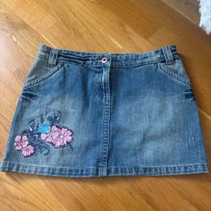 Blå jeanskjol med broderade blommor - Säljer denna för den är för stor. Skulle säga den är storlek s-m. Jeanskjol från Papaya. 