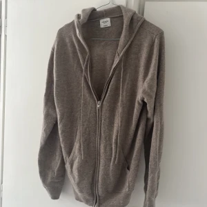 Beige hoodie i kashmir från John Henric - Använd 6-7 gånger, Priset ej hugget i sten. Nypris 2499kr! Mjuk och lyxig beige hoodie från John Henric i kashmir. Tröjan har huva, dragkedja framtill och två fickor. Perfekt för dig som gillar chill och stilren look. Långärmad och med ribbade muddar för extra komfort.