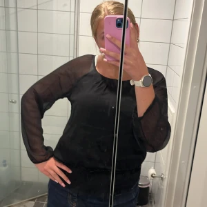 Svart blus från Vero Moda, storlek L - Säljer en svart blus från Vero Moda i storlek L. Blusen har transparenta långärmade ärmar och rundad halsringning. Tunn blus, som är superskön!