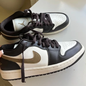 Nike Air Jordan 1 Low brun svart vit - Snygga Nike Air Jordan 1 Low sneakers i svart brunt o vitt skinn med bruna detaljer och klassisk swoosh. .i