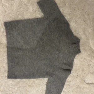 Grå stickad polotröja från Zara - Mysig grå stickad polotröja från Zara i storlek M. Tröjan har en hög krage och korta ärmar, perfekt för kyliga dagar. Enkel och stilren design som är lätt att matcha med olika outfits. Välanvänd men i bra skick💕💕