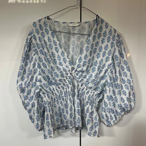 Vit och blå blus med v-ringning - Supersöt blus med v-ringning från HM. Finns ingen lapp med storlek då jag köpte den begagnat för ett tag sen, men passar mig som bär S/M. Blusen finns inte längre på hm hemsida. Säljs då den inte kommer till användning längre!💞