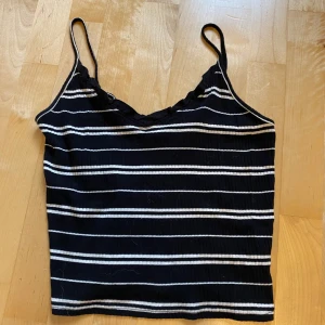 Svartvit randig linnetopp BikBok XS - Snygg svart och vit randig linnetopp från BikBok i storlek XS. Toppen har smala axelband och är ribbad i materialet, vilket ger en cool och avslappnad vibe. Perfekt att matcha med jeans eller shorts för en enkel och stilren look.