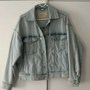 Ljusblå jeansjacka från H&M oversize - Snygg oversize ljusblå jeansjacka från H&M i storlek XS. Klassisk modell med två bröstfickor med knappar, silverfärgade detaljer och avslappnad passform. Perfekt att slänga över en hoodie eller t-shirt för en chill look. Säljer 300kr, ordinarie 599kr