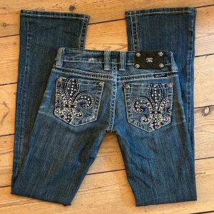 Miss Me  - Miss Me jeans🤍 2010s vintage, bootcut med tjocka sömmar + ikoniska fickor (fleur-de-lis & rhinestones). rare att hitta i Sverige❕🙌🏻 mått: midjemått rakt över 35 grenhöjd 17 innerbenslängd 79. bra skick, lite slitna längst ner vid benen (tillhör designen i övrigt). lägg gärna prisförslag😇