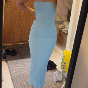 Bandeau midi klänning - Säljer en ljusblå, bandeau midi klänning med slim passform. Klänningen är ribbad och har en snygg slits baktill. Köptes i somras och är använd endast en gång. 