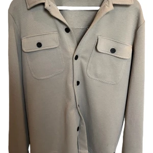 Beige overshirt från Only & Sons XS passar S - Snygg beige overshirt från Only & Sons i storlek XS men passar S. Skjortan har två bröstfickor med lock och svarta knappar framtill. Perfekt att bära öppen över en t-shirt eller stängd för en clean look. Materialet känns mjukt och slitstarkt den är bara testad men kan inte lämna tillbaka längre🙌😁. 