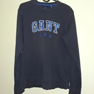 Mörkblå GANT sweatshirt med tryck - Snygg mörkblå sweatshirt från GANT med broderad logga och tre blå stjärnor framtill. Tröjan har rund hals, långa ärmar och är gjord i mjuk bomull. Perfekt för en chill och stilren look.
