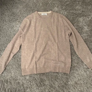 Beige kashmirtröja  - Supermjuk beige tröja i kashmir. Klassisk rund halsringning och långärmad modell med ribbade muddar. Perfekt för dig som gillar en clean och stilren look med lyxig känsla.