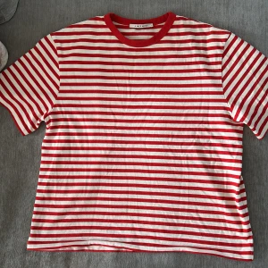 Randig t-shirt från A Day's March - Säljer en t-shirt från A Day's March med röda och vita ränder. Tröjan är i storleken s, men skulle säga att den upplevs som lite större i storleken. Har inte använts mycket och är i bra skick