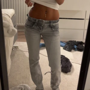 Grå straight jeans - Säljer ett par grå jeans med snygg tvätt och Modellen är straight fit med klassiska fem fickor och dubbla knappar i midjan. Perfekt för dig som gillar en chill och stilren look. Passar till både sneakers och boots.