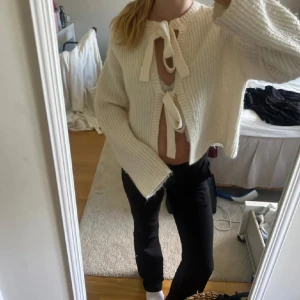 Vit stickad kofta med knytband - Superfin vit stickad kofta med två stora knytband framtill. Koftan är croppad med breda ärmar och ribbad struktur, perfekt för lager-på-lager och chill vibes.