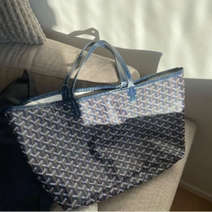 Blå shoppingväska  - Säljer en stor och rymlig shoppingväska i blått med ikoniska mönster. Väskan har två handtag i blått och är perfekt för dig som vill ha plats med allt. Klassisk och stilren design med lyxig känsla.