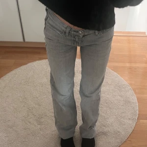 Ljusgrå raka jeans från Gina - Säljer ett par ljusgrå jeans från Gina med klassisk femficksdesign och raka ben. Jeansen har låg midja och är tillverkade i ett mjukt jeanstyg som ger en avslappnad vibe. Perfekta för dig som gillar en enkel och stilren look.