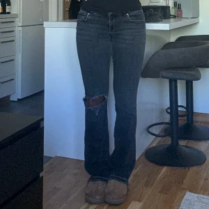 Lågmidjade bootcut jeans - Säljer ett par svarta/mörkgrå bootcut jeans ifrån Zara som jag själv gjort en slitning på vid knät och sprättar upp längst ner för att få dem längre. För referens är jag 174. Jeansen är i storlek 42 men passar mig som vanligtvis har storlek 40 i Zara jeans 