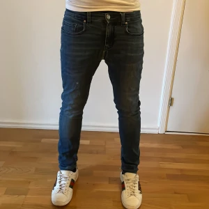 Mörkblåa skinny jeans - Säljer ett parm mörkblåa jeans med snygga slitningar. Modellen är skinny fit med låg midja och klassiska fem fickor. Jeansen har stretchigt material för extra komfort och en modern look. Kom dm vid minsta fundering. Fast pris! Plus en liten skada vid baksidan! Inget hål. Går och sy ihop. Defekter kommer…