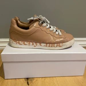 Beige sneakers från See By Chloé - Snygga beige sneakers från See By Chloé i skinn med vita snören och klassisk låg modell. Skorna har en vågig detaljsöm längs sidan och vit platt sula. Väldigt sköna sneakers som jag använt en del. Fortfarande väldigt fina! Kartong ingår!