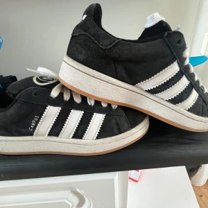 Svarta Adidas Campus sneakers - Säljer ett par svarta Adidas Campus dem är i bra skick bara lite smutsiga och en skada i hälen men den syns inte när du har på dig dem. Du skulle nog behöva borsta upp mockan anars är dem i bra skick