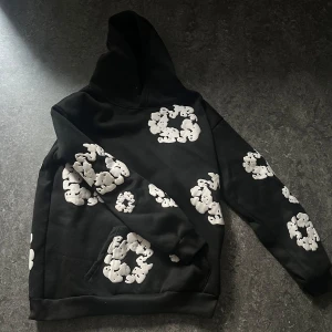 Svart hoodie med vita blommor från Denim Tears - Säljer en svart hoodie från Denim Tears med vita blommor som tryck. Jag säljer då jag inte använder den, kom gärna med bud, skriv för fler bilder och priset kan även diskuteras. 