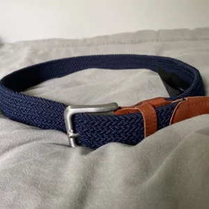 Blått flätat bälte från Jack & Jones - Snyggt blått flätat bälte från Jack & Jones med detaljer i brunt skinn och silverspänne. Perfekt accessoar för att lyfta din outfit. Bältet har längd 80 och klassisk design.