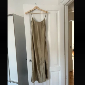 Champagne grön långklänning med slits - Säljer en elegant långklänning i champagne grön färg med smala axelband och slits på sidan. Klänningen går ner till anklarna på mig som är 172 cm lång. Pris kan diskuteras 