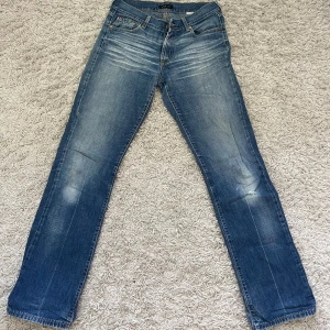 Blå jeansbyxor vintage - Säljer ett par vintage  blå jeansbyxor från Bikk Bok med normal passform. Byxorna har fem fickor, dragkedja och knapp framtill samt snygga slitningar och ljusare partier på låren för en trendig look. Sitter som en storlek 36