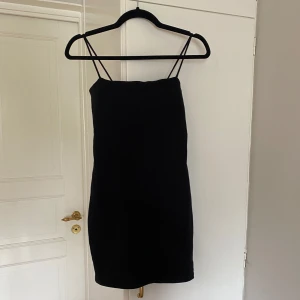 Svart kort klänning från Gina Tricot - Säljer en svart, enkel och stilren kort klänning från Gina Tricot. Klänningen har smala axelband och rak passform, perfekt för en trendig look. Passar dig som gillar minimalistisk stil. Inga tydliga defekter, endast använd en gång. Hör av er vid frågor 💕