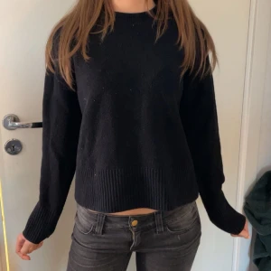 &Other stories tröja - En svart stickad tröja med rund hals och långa ärmar. Tröjan har ribbade muddar vid ärmslut och nederkant, vilket ger en enkel men stilren look. Perfekt att matcha med jeans eller kjol.
