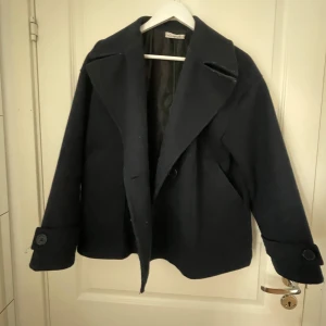 Mörkblå ullkappa från Design by Si - Säljer denna mörkblåa kappa från Design by si. Storlek M/L. Jackan saknar ena knappen på framsidan men går fortfarande att stänga. 💕