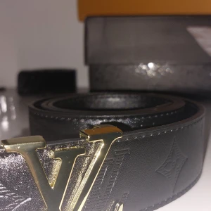 Lvbälte - Snyggt svart skärp från  i skinn med präglad -logga och ikoniskt -spänne i matt svart metall. Bältet har diskreta monogramdetaljer längs hela remmen och stilrena sömmar. Perfekt accessoar för att lyfta din outfit.