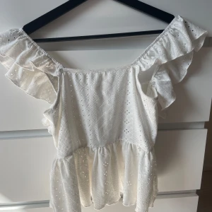 Vit volangblus från Shein - Superfin vit blus från Shein i storlek XS. Toppen har volangdetaljer längs axlarna, broderat hålmönster och knytning i ryggen. Den är använd fåtal gånger!! den sitter jättebra överallt! 💗