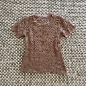 Stickad brun spetsblus med kort ärm - Supersöt brun stickad blus med korta ärmar och spetsdetaljer vid halsringningen. Blusen har ett genombrutet mönster och är figurnära med ribbad nederkant. Skicket är 10/10 och har inga defekter. Tyvärr inget märke men materialet är av hög kvalitet och nopprar ej. Skriv gärna om ni har några frågor!!