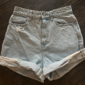 Ljusblå jeansshorts från Zara - Snygga ljusblå jeansshorts från Zara med hög midja och avslappnad passform. Shortsen har slitna detaljer, uppvikta benslut och klassiska fem fickor. Storlek 36💕
