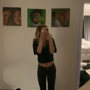 Grön glittrig croppad topp - Säljer en grön glittrig croppad topp med korta ärmar. Toppen har massor av paljetter och glittrar upp HELA rummet. Den sticks ej då tyget inuti är mjukt och skönt! Modellen är figurnära och toppen slutar precis ovanför midjan. Köpte 2022 och användes nyåret 22-23. Annars oanvänd. 