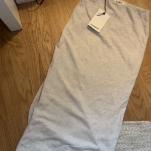 Beig kjol  - Enkel och stilren beige kjol från Pull&Bear i storlek S. Klänningen har rak passform, mjukt bomullsmaterial och en snygg slits nedtill för extra rörelsefrihet. Perfekt för dig som gillar minimalistisk och clean stil. Helt ny med prislapp kvar.