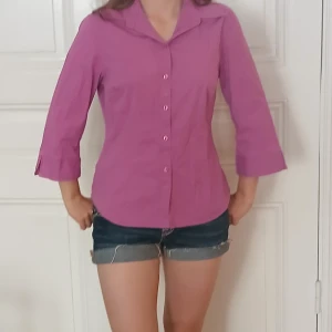 Lila skjorta från Connect - Snygg lila skjorta från Connect med trekvartsärm och klassisk krage. Skjortan har knappar framtill och är i ett mjukt bomullstyg. Perfekt för dig som vill ha en färgklick i garderoben! Står storlek 42 men jag på bilden bär ofta xs/s så skulle säga att den passar en M❤️