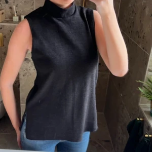 Svart ärmlös polotopp - Snygg svart polotopp utan ärmar med hög krage.