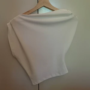Vit one shoulder topp från Zara XS - Supersnygg one shoulder topp från zara i storlek xs. Toppen är helt oanvänd.