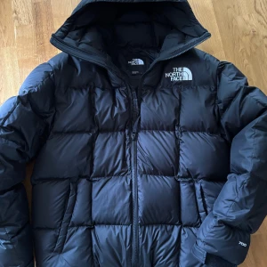 Svart dunjacka The North Face L - The North Face Men’s Lhotse Down Hooded Jacket – stl L, nästan nyskick Pris: 2 500kr (nypris ca 3 800kr) kan tänka mig diskutera pris.  Säljer min The North Face Lhotse dunjacka som jag köpte förra vintern. Den är använd endast ett fåtal gånger då den visade sig vara för stor för mig och jag var tvungen att istället använda min gamla vinterjacka. Jackan är i nästan nyskick, utan några defekter, fläckar eller skador.