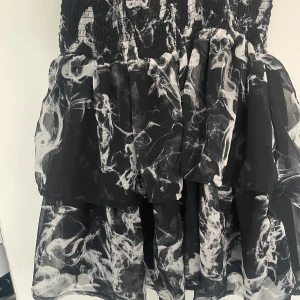 Svartvit kortklänning från KappAhl - Cool svartvit kortklänning från KappAhl med abstrakt mönster. Klänningen har smock upptill och volangig kjol i flera lager. Lätt och luftig känsla, perfekt för dig som vill sticka ut med en unik look. Skriv för mer info