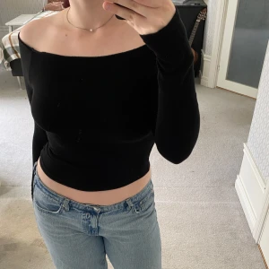 Svart offshoulder ribbad topp - Säljer en svart, ribbad offshoulder topp med lång ärm och croppad passform. Hål för tummen på båda ärmarna (se sista bild).    Använt fåtal gånger. Hel och fräsch, men billigt material såklart då den är från Shein 