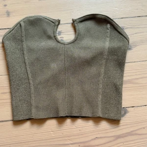 Olivgrön ribbad tubtopp H&M Edition XS - Säljer en olivgrön ribbad tubtopp från H&M Edition i storlek XS. Toppen har bandeau-modell och är tillverkad i ett stretchigt, stickat material som sitter tight och bekvämt. Perfekt att styla med höga jeans eller kjol 