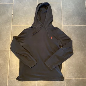 Svart hoodie från Polo Ralph Lauren - Säljer en svart, tunn Ralph Lauren hoodie. Perfekt för lager-på-lager eller som ett lättare alternativ. Mjukt material, klassisk design med dragskojustering i huvan och broderad logga. Perfekt för en avslappnad och bekväm stil.       Storlek: M   |  Skick: 9/10 (inga defekter).            Om du har några funderingar eller intresse kontakta mig!  Skickar gärna fler foton om det önskas.