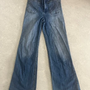 Blåa wide jeans med stora bakfickor - Snygga blå utsvängda jeans 