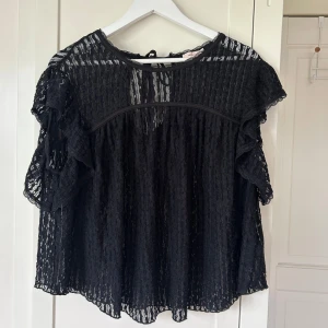 Svart spetsblus med volangärmar - Jättefin och söt spetstopp, kan kläs med ett linne eller bh under! Köpte från Nelly, orginalpriset 299kr. Toppen säljs längre inte i svart på hemsidan utan bara vit!